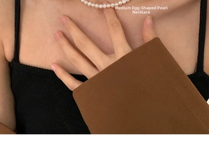 Macro detail of medium oval freshwater pearls on 14K gold filled necklace worn on neck