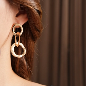Close-up of gold interlocking hoop earrings worn by a model with soft lighting
