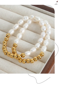 Detail of freshwater pearl and 18k gold bead bracelet on a beige velvet jewelry box tray