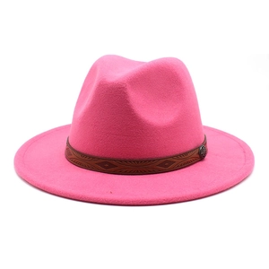 Detail of bright pink wool fedora featuring a carved brown leather band and metal buckle