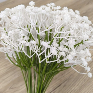 Close-up of white artificial gypsophila flowers with green stems on a wooden table