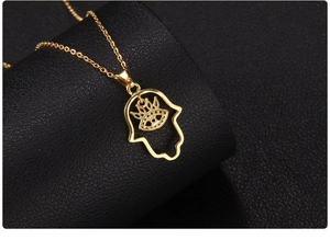 Macro view of the back side of a gold-plated Hamsa Hand and Evil Eye pendant