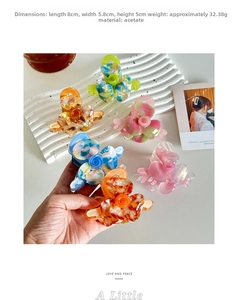 Macro view showing dimensions and weight of acetate floral hair claw clips on white tray