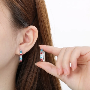 Détail de boucles d'oreilles en U argentées avec pierres multicolores sur un mannequin