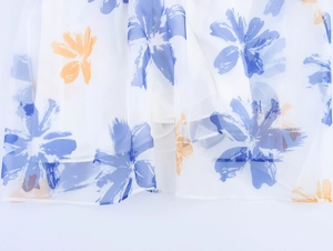 Detail eines eleganten blauen Aquarell-Blumendrucks auf leichtem weißem Organzastoff