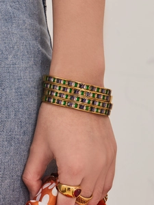 Detail of 18K gold plated bangles featuring colorful square zircon stones on model wrist