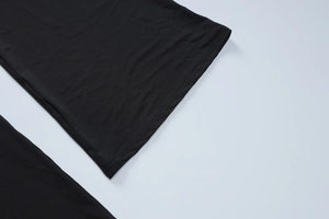 Detailed close-up of double-needle hem stitching on black high-stretch knit trousers