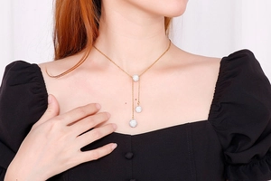 Close-up of gold ball necklace with clear crystals worn by a model in natural lighting