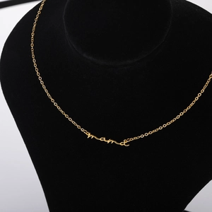 Detailed view of cursive Mama pendant on a gold chain necklace displayed on a black stand