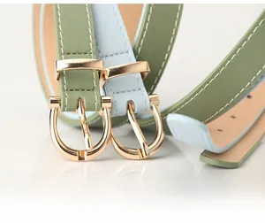 Close-up of minimalist PU leather belts in avocado green and light blue with gold U-buckles