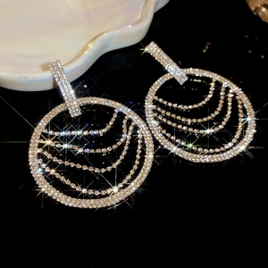 Gros plan sur des boucles d'oreilles rondes argentées avec cristaux pavés et franges