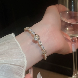 Detailed close-up of 14k gold plated flower bracelet with zircons on model wrist