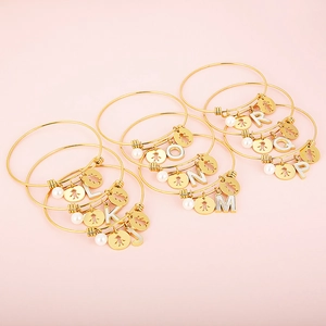 Detailed close-up of golden adjustable bracelets with letter charms and pearl accents
