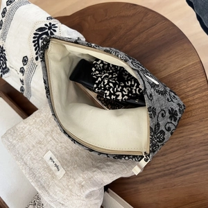 Detail of linen makeup bag with vintage floral pattern and internal storage space