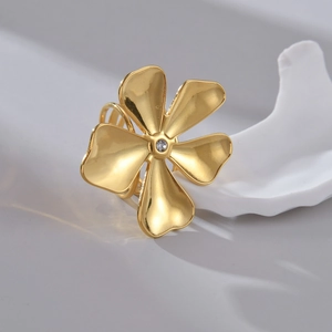 Macro detail of golden flower ring with a central sparkling zircon on ceramic background