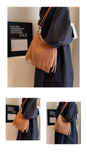Detail of bohemian suede bucket bag with long tassels and vintage embroidery elements