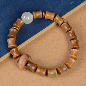 Détail macro du bracelet en perles de bois de santal avec orbe lumineux et entretoises dorées