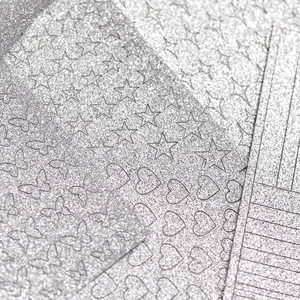 Makroansicht silberner Glitzer-Nagelsticker mit Stern-, Schmetterlings- und Herzmotiven