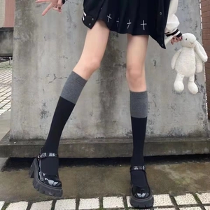 Gray and black contrast crew socks paired with black Mary Jane shoes on a concrete background