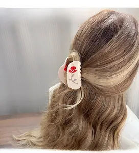 Detail of cream hair claw clip with vintage red rose print on a woman's brown wavy hair