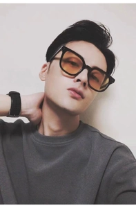 Close-up of oversized square sunglasses with black frame and orange lenses on a model