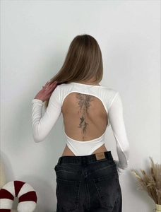 Detail view of the large circular back cutout on a white long-sleeved bodysuit