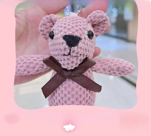 Dettaglio portachiavi orsetto rosa lavorato a maglia con fiocco e texture crochet