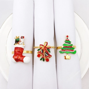 Close-up of golden Christmas napkin rings with stocking, bell, and tree designs on white plates