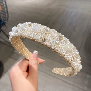 Detailed close-up of a wide headband with micro pearls and sparkling rhinestones