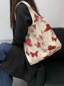 Dettaglio del ricamo farfalla rossa su borsa shopping in rete bianca con trama 3D