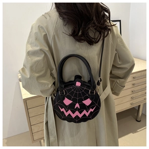 Detail of a black pumpkin-shaped bag with pink embroidery on a model wearing a trench coat