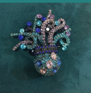 Detailed close-up of retro flower basket brooch with colorful rhinestones on velvet
