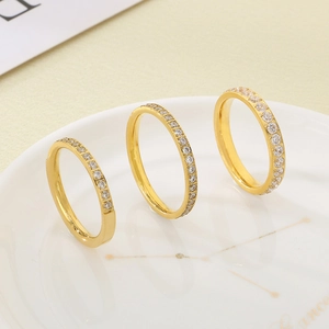 Three gold stainless steel eternity rings with clear zircon inlay on a white ceramic plate
