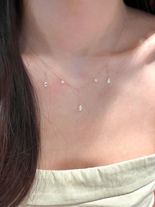 Close-up of gold tassel necklace with zircon water drops worn on model neckline