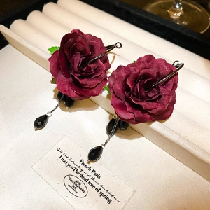 Detailed shot of dark red fabric rose earrings with black crystal teardrop pendants