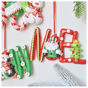 Close-up of NOEL festive clay ornament with Santa and penguin on a snowy pine branch