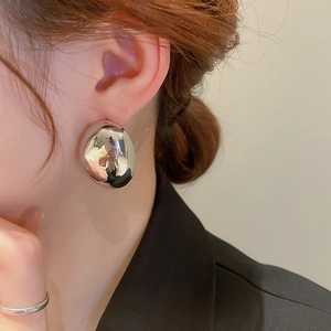 Close-up of irregular liquid metal stud earrings with polished silver mirror finish