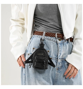 Mini black leather backpack coin purse with gold logo clipped to blue denim jeans