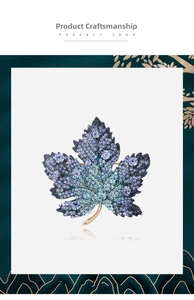 Close-up of maple leaf brooch with gradient blue and purple crystals on white display