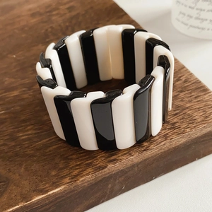 Macro shot of black and white striped resin stretch bracelet on dark wood tray