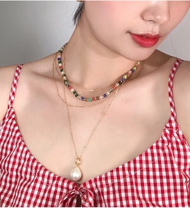Detailed view of layered necklaces featuring colorful beads and a pearl pendant charm