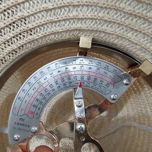 Detail view of straw hat measuring head circumference from 49cm to 62cm with a metal tool