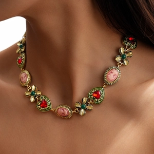 Detailed close-up of vintage cameo pendant with red heart gemstone and floral accents