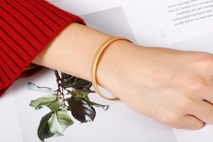 Close-up of matte golden titanium steel bracelet on wrist with elegant red sweater cuff