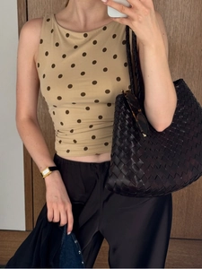Détail d'un haut sans manches à pois kaki et d'un sac cabas en cuir tressé chic