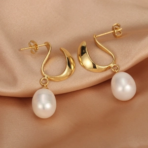 Macro shot of 18K gold plated U-shaped earrings with white freshwater drop pearls on silk