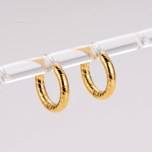 Detailed view of gold hoop earrings with spiral texture on a transparent acrylic display