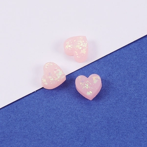 Pink heart-shaped synthetic opal pendants with holographic glitter on a blue and white background
