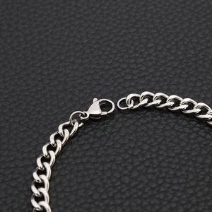 Macro detail of a silver stainless steel curb chain bracelet with a durable lobster clasp