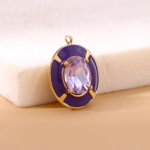 Macro view of purple enamel charm with oval gemstone and gold plated metal details